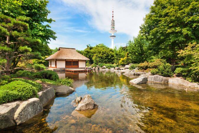 The Japanese garden in the Planten and Blom park in Hamburg with a pond and the television tower in the background