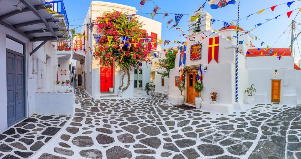 Street in Mykonos City with Colorful flags as decoration.