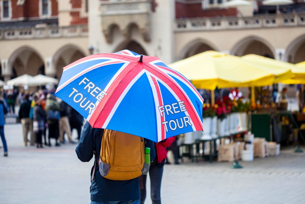 A person standing in a public place with an umbrella on the free tour