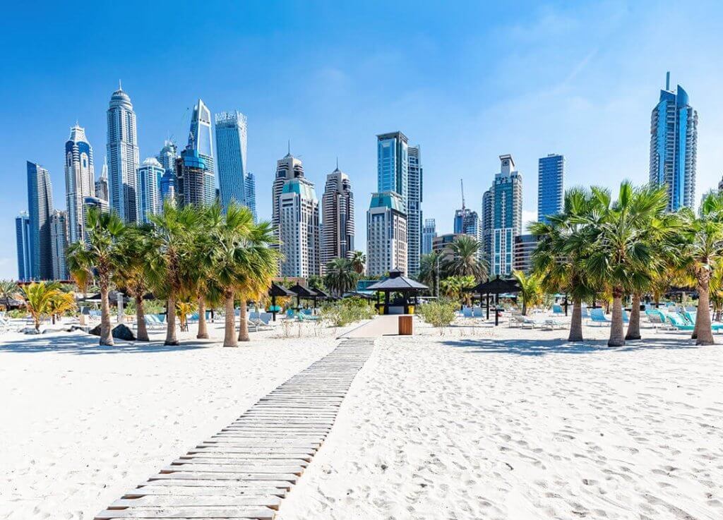 Boardwalk at Palm Jumeirah Beach with the Dubai Skyline in the background.