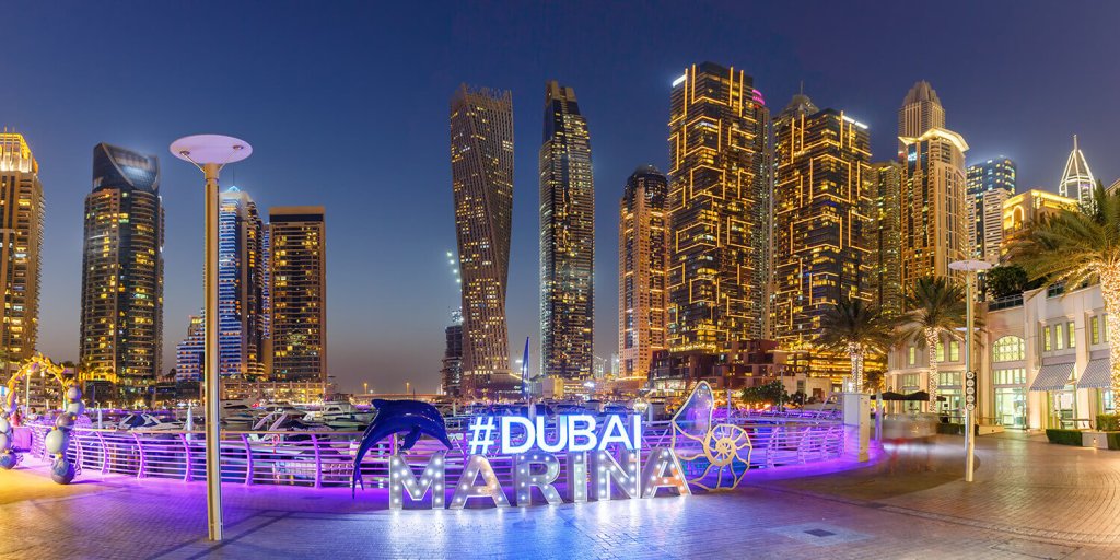 Illuminated Dubai Marina letters at night with the Dubai skyline in the background