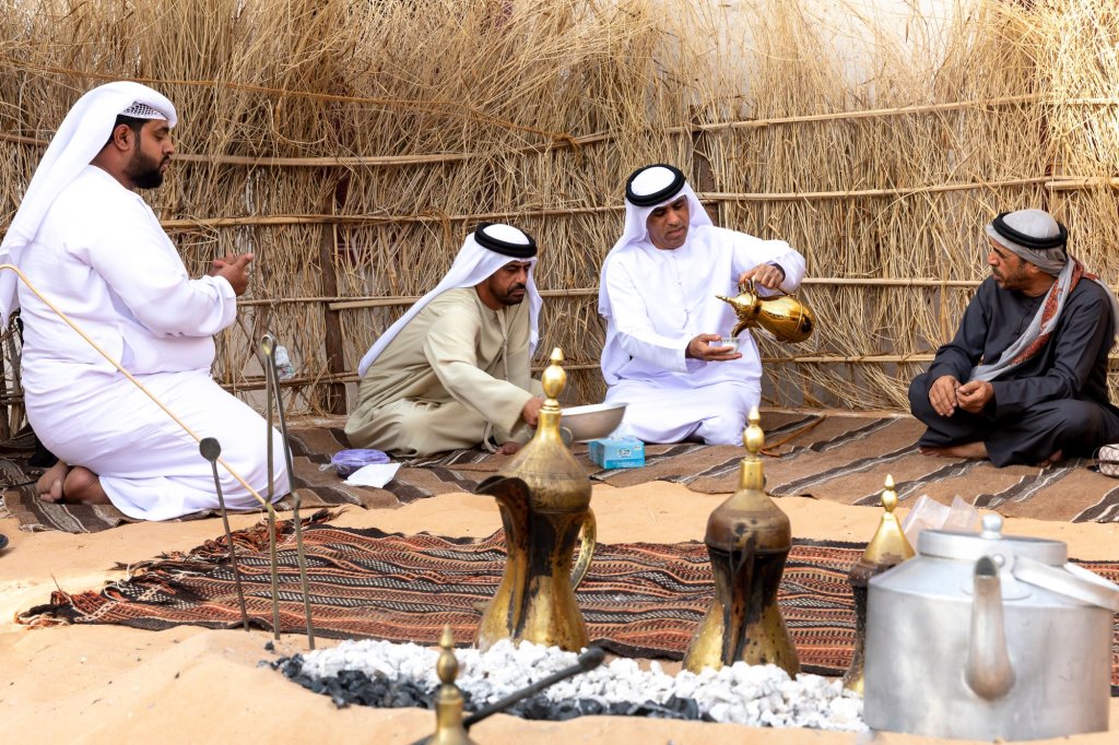 Arabic men gather together and drink coffee seating in traditional Bedouin tent.