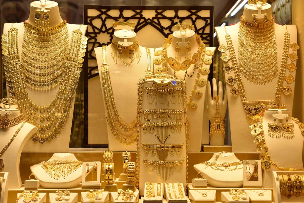 Section of a shop window full of gold jewelry, such as necklaces, earrings and bracelets.