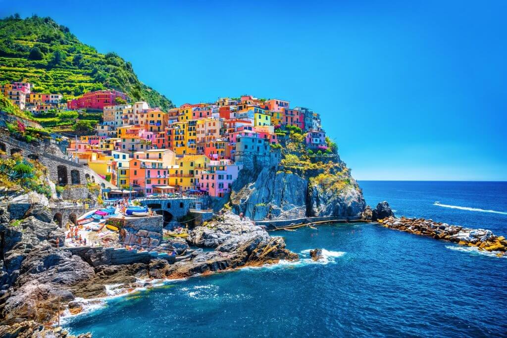 View of the town Cinque Terre with col,orful houses on a rock next to the ocean.