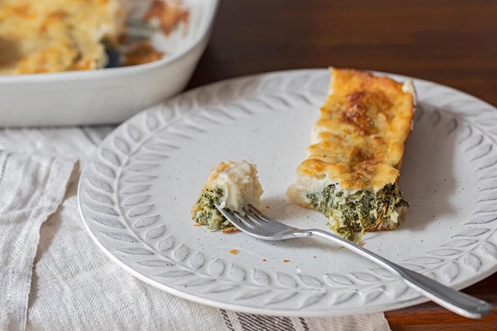 A piece of sliced crespelle with a spinach and ricotta filling