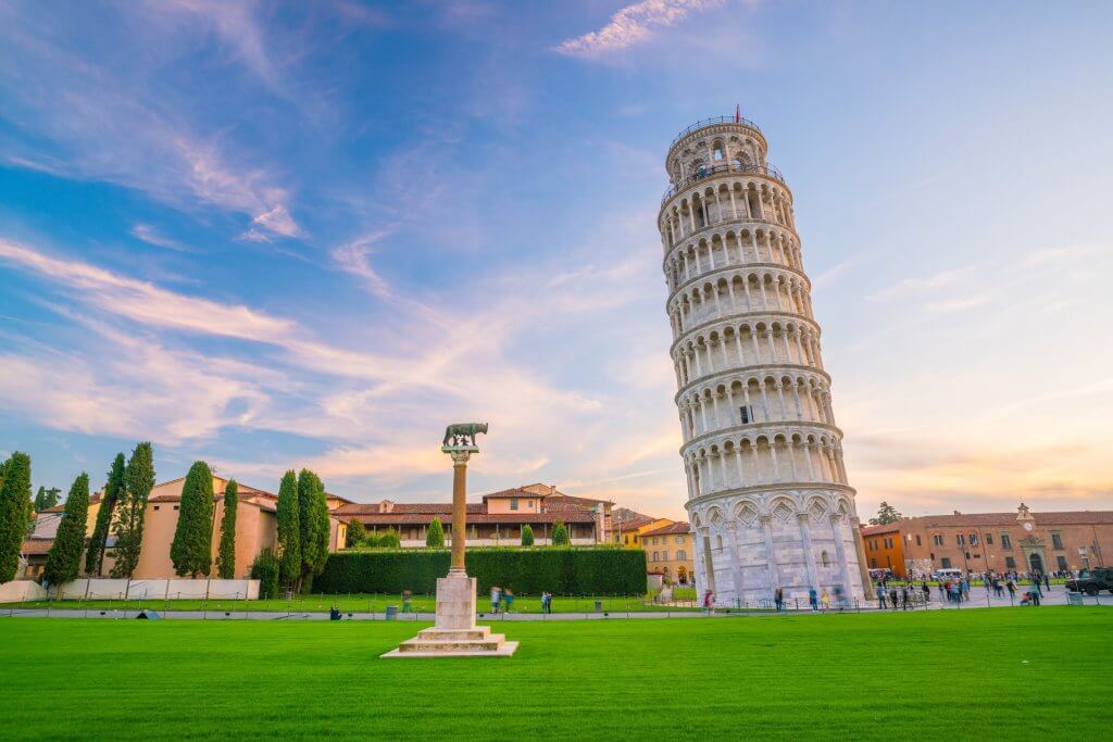 Leaning Tower of Pisa with blue sky and green grass in the foreground.
