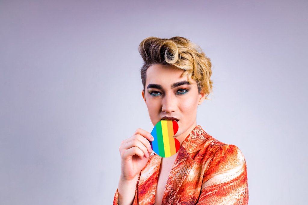 A cross-dresser holding a heart of LGBT colors in the hand.