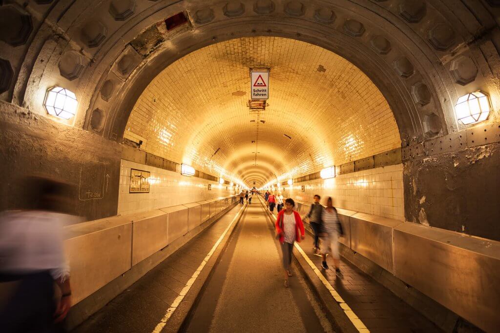Pedestrian path of the illuminated Elbe tunnel with some passers-by