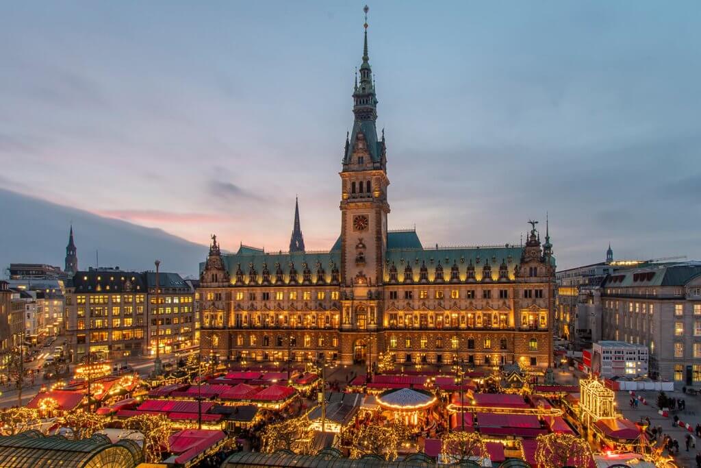 View of the front of the entire town hall in Hamburg with a Christmas market on the square in front