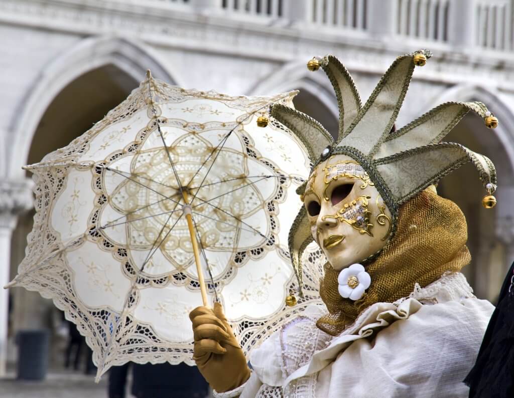 disguised person with traditional Venetian carnival mask and costume in white.
