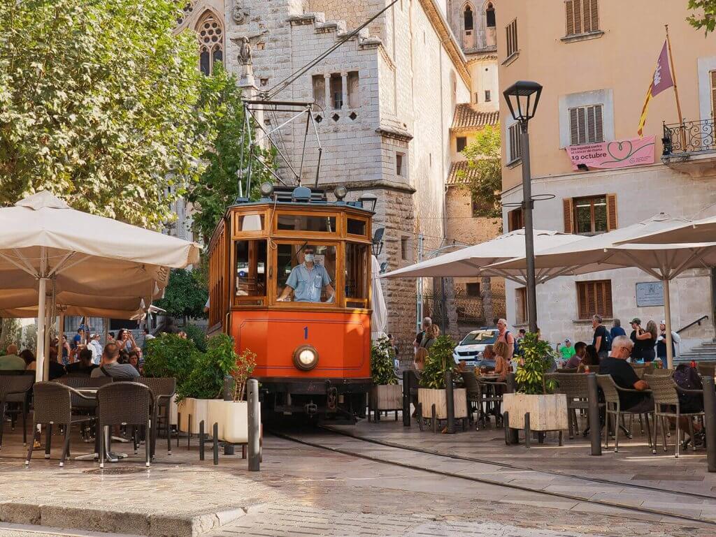 Front of the red, historic train passing through the town of Soller.