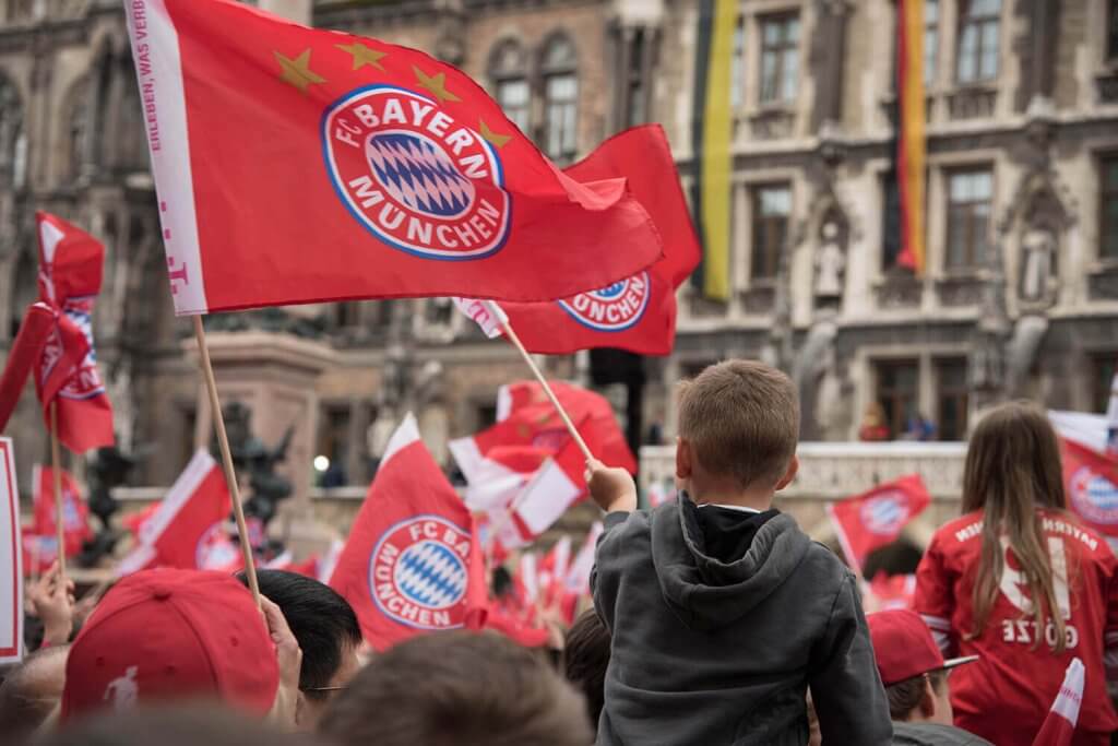 Bayern Munich fans on a public square celebrating with the fan flags and football shirts.