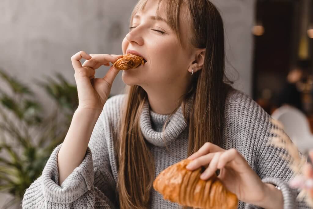 Young woman enjoying the taste of her croissant.