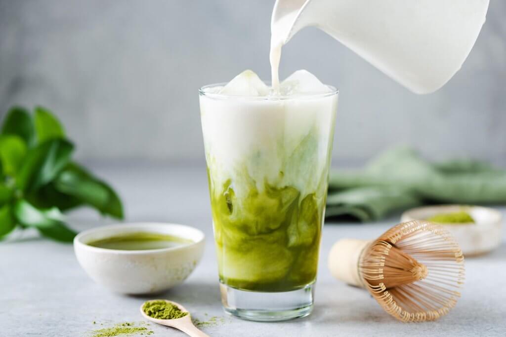 Adding Milk into a glass of Matcha Latte.