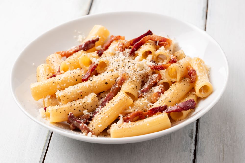 Pasta without sauce, served only with parmesan and bacon in a plate