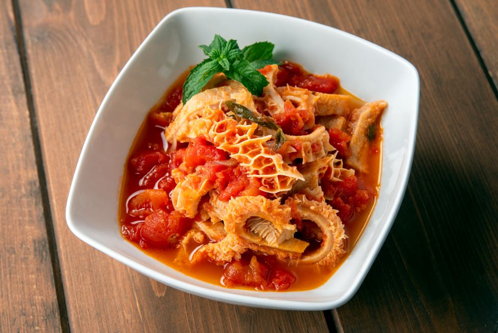 White bowl with a dish of stomach, trippa cooked in a tomato sauce