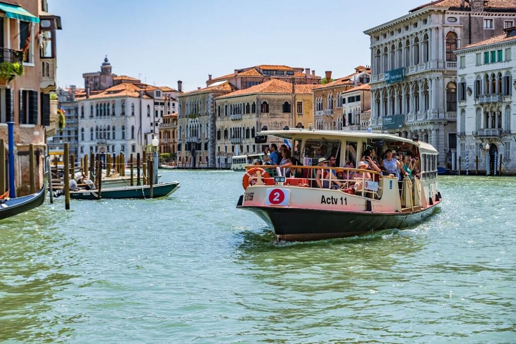 Venetian water bus with many passengers traveling on the Grand Canal.
