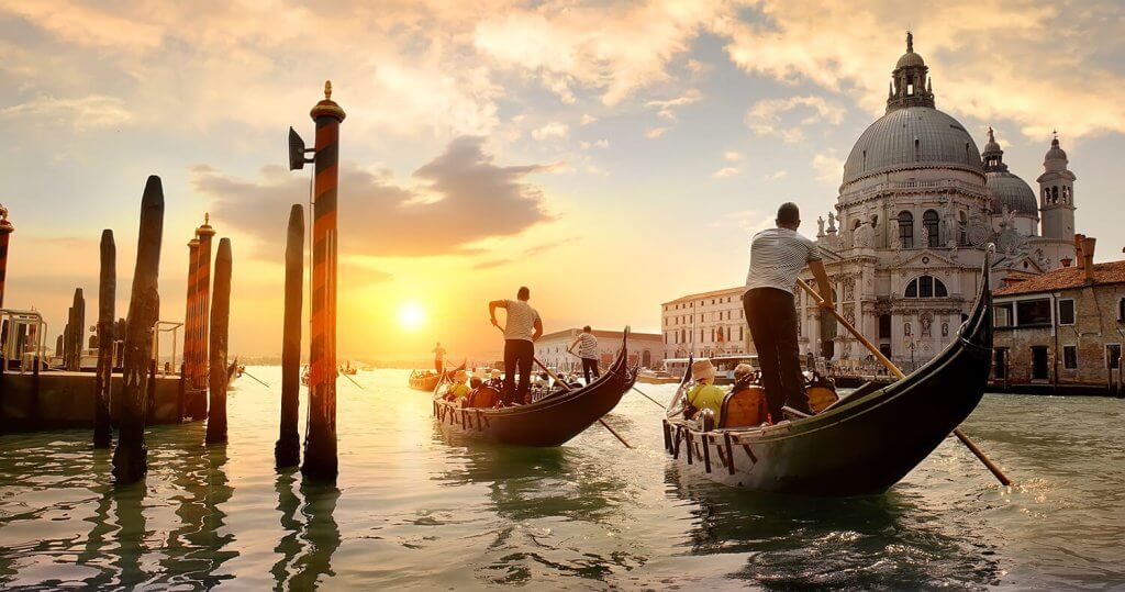 Two gondola riders on a canal at sunset.