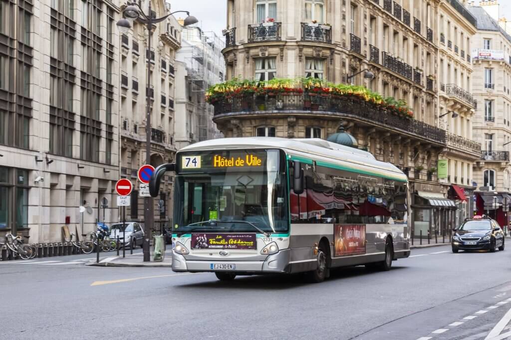 A passenger bus driving in the city center of Paris.