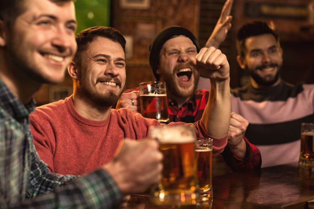 Cheerful young male friends having fun in the beer pub and celebrating the victory of their favourite team.
