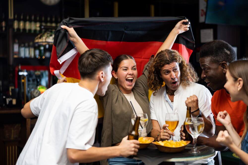 Enthusiastic German football fans scream with joy in a beer bar.