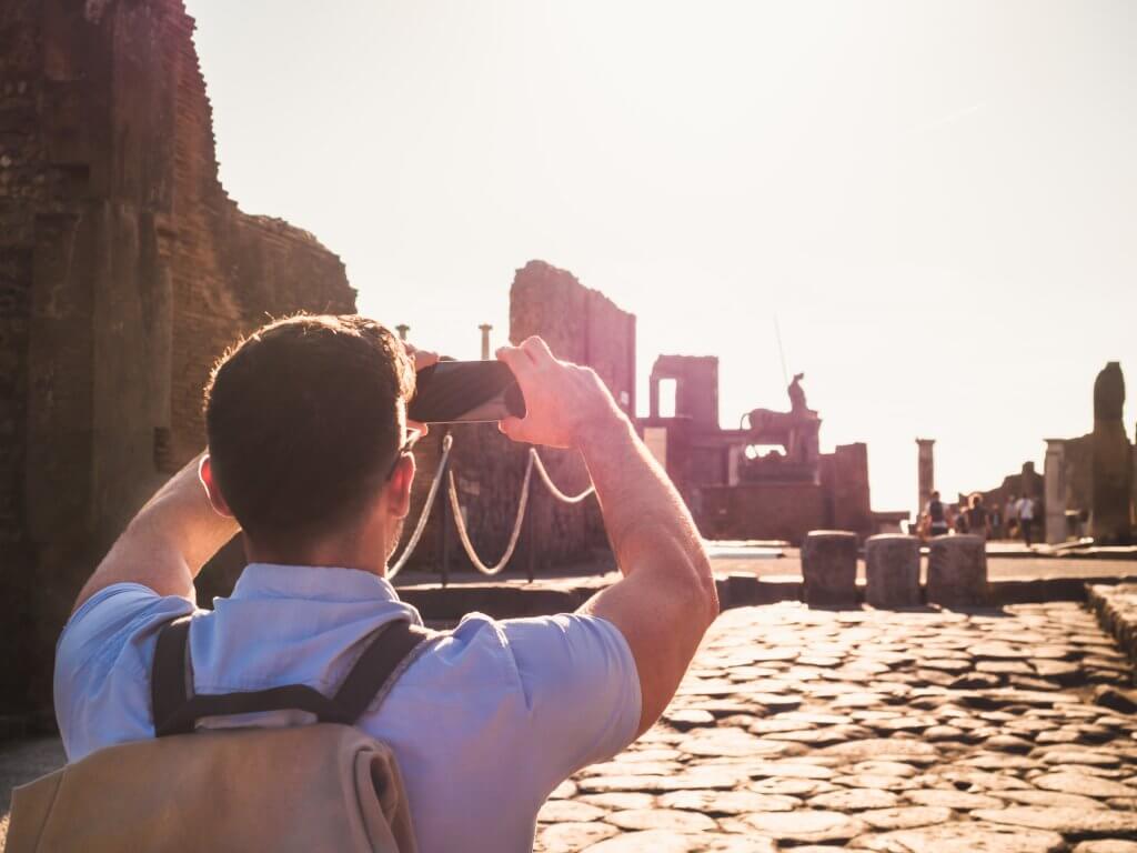 A young man takes a photo of ruins in Pompeii