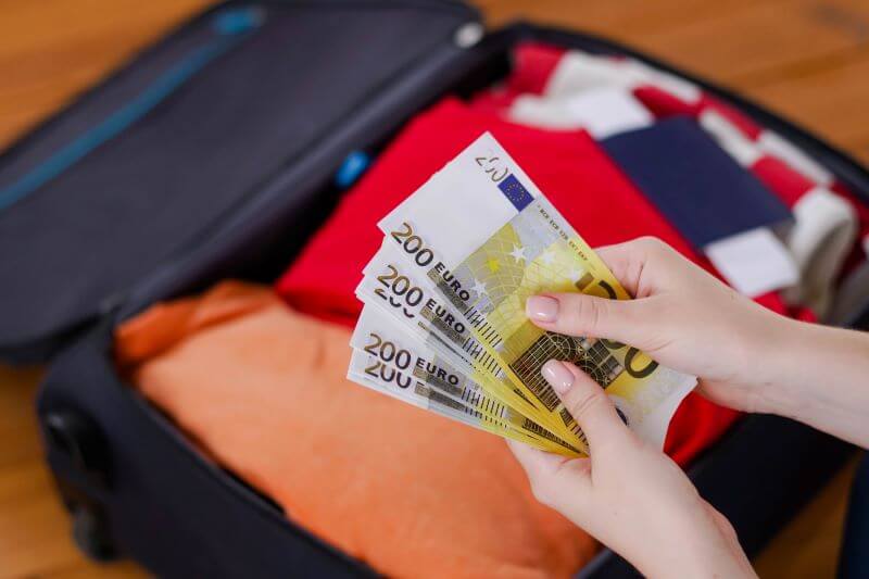 Open suitcase and hands holding Euro notes