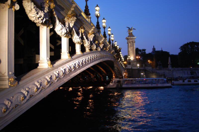 Cruise ship on river seine with bridge by night